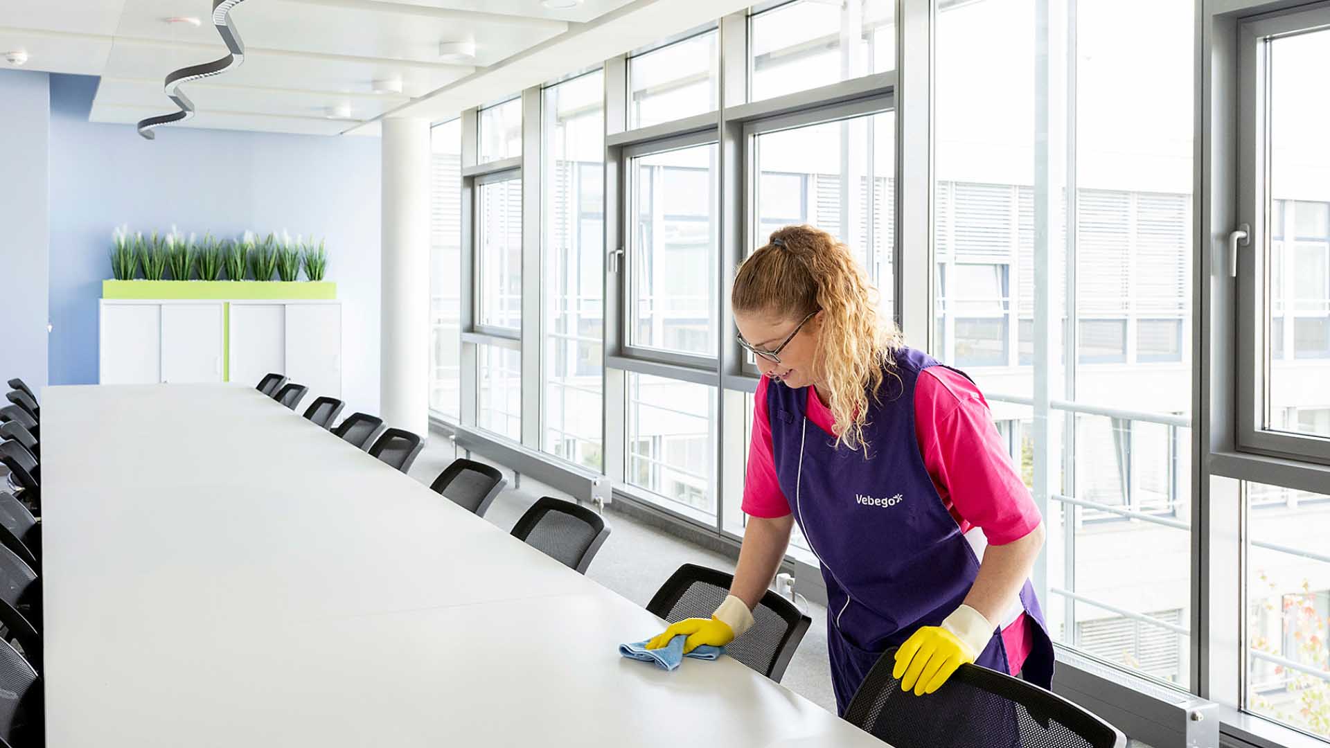 Reinigungskraft wischt Tisch im Konferenzraum