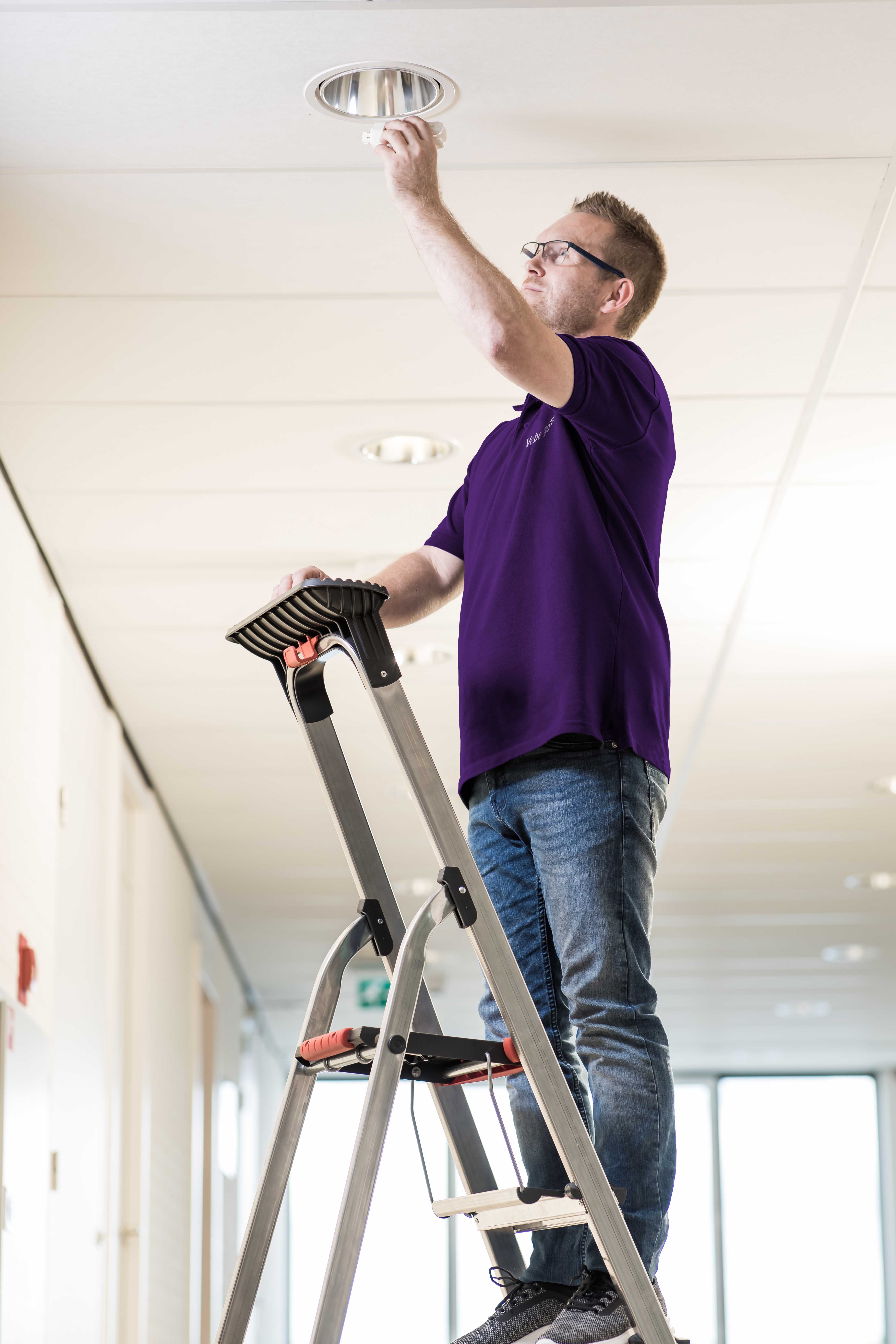 Hausmeister wechselt Leuchtmittel aus