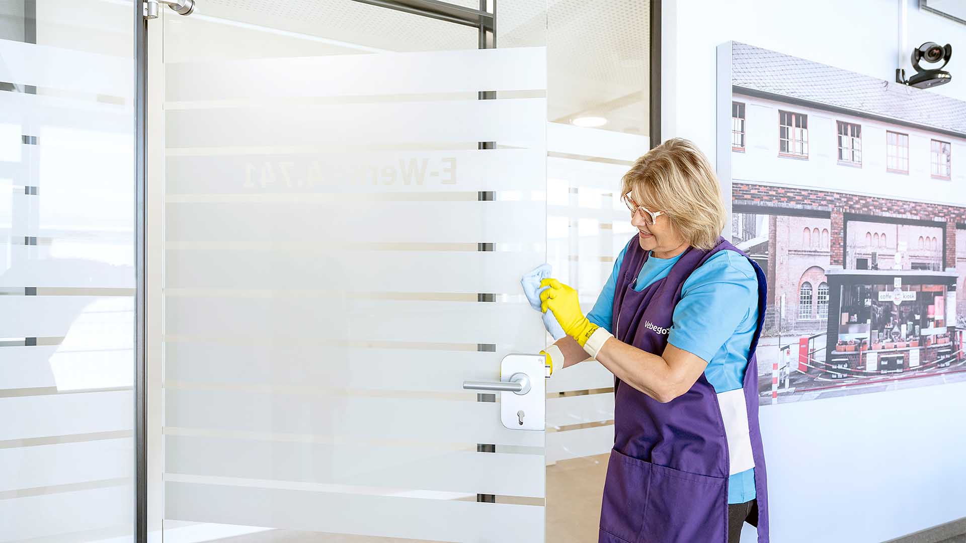 Reinigungskraft reinigt Türgriff