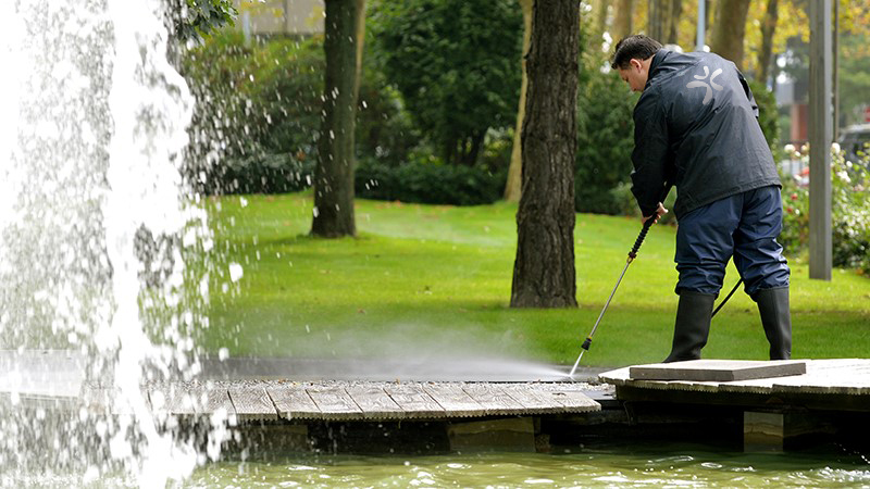 Mitarbeiter reinigt Außenanlage mit Hochdruck