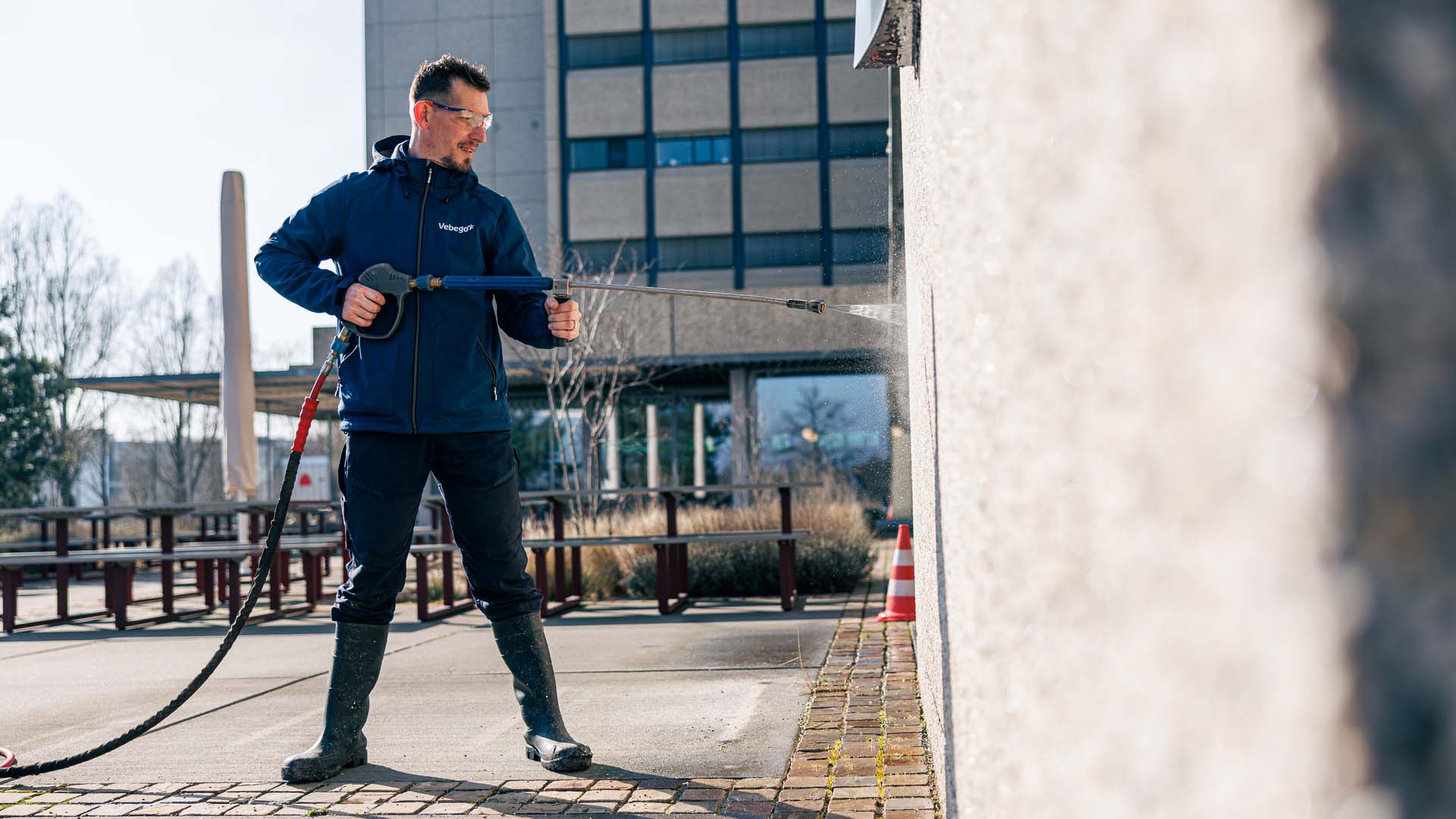 Mitarbeiter reinigt Fassade mit Hochdruckreiniger