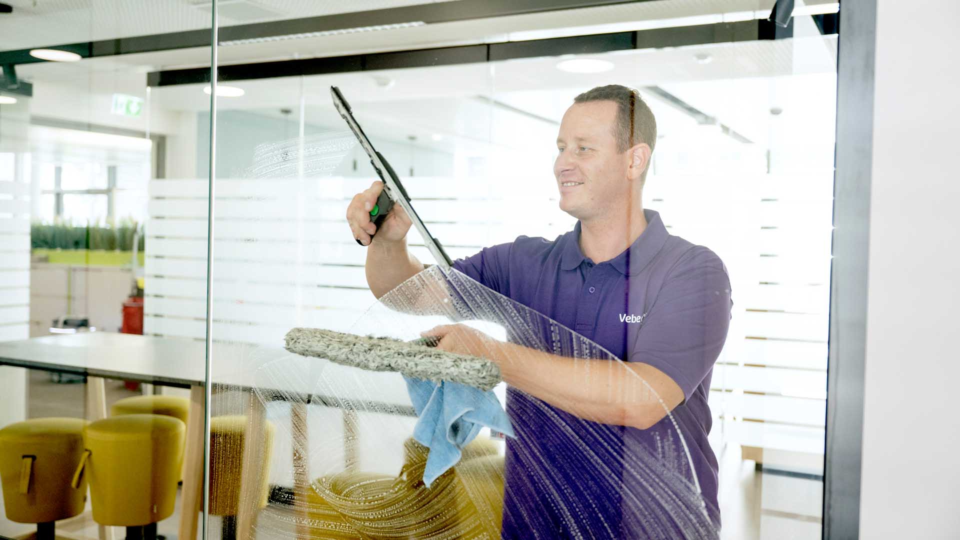 Glasreiniger reinigt Scheibe von Büro